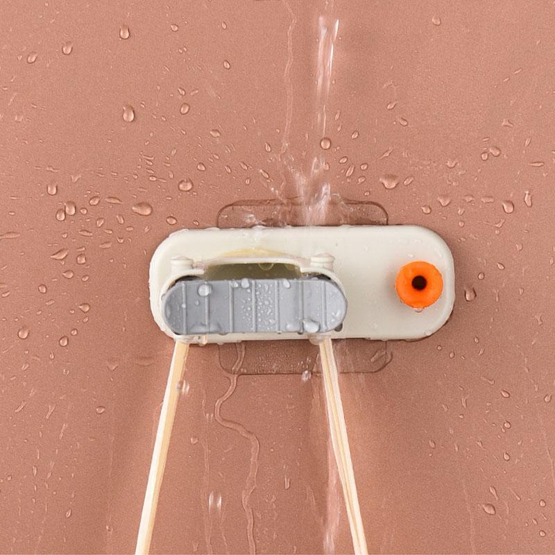 Space-saving wall organizer for brooms and mops, features an integrated hook for extra storage