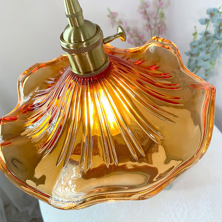 "Hibiscus flower-shaped pendant light in brass and glass, adds elegance and vibrancy to stylish room decor."