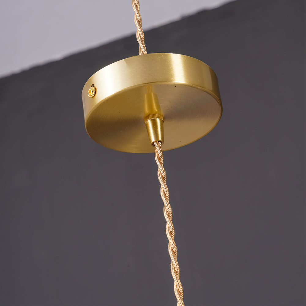 "Hibiscus flower-shaped pendant light in brass and glass, adds elegance and vibrancy to stylish room decor."