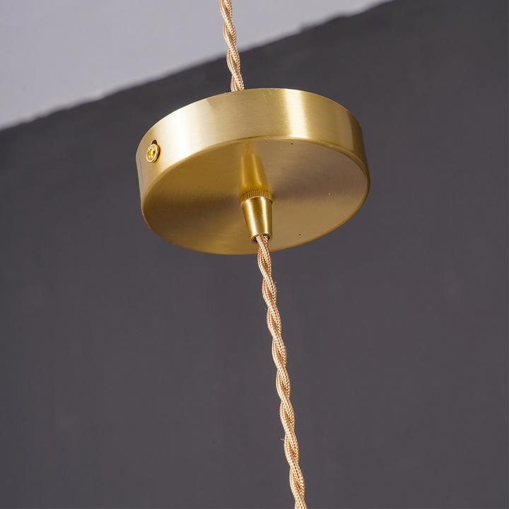 "Hibiscus flower-shaped pendant light in brass and glass, adds elegance and vibrancy to stylish room decor."