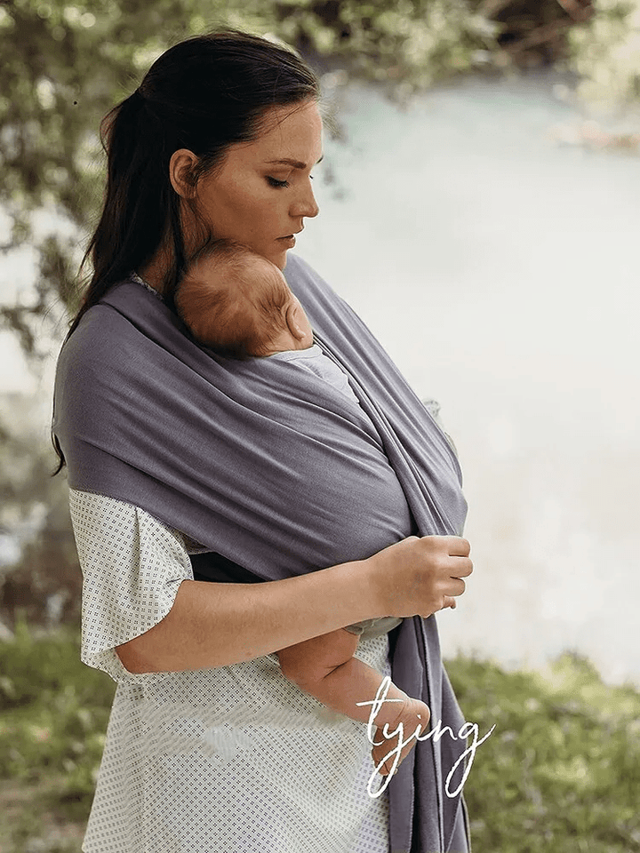 "Unisex ergonomic baby wrap carrier, grey, enveloping baby and parent comfortably for hands-free convenience."