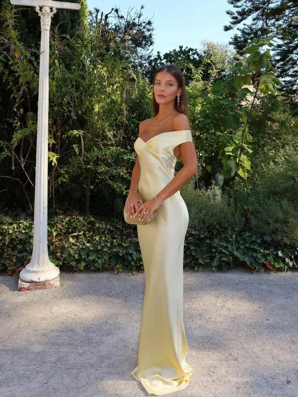 Women's off-shoulder yellow maxi dress with matching clutch; chic design, flowing silhouette, perfect for elegant events.