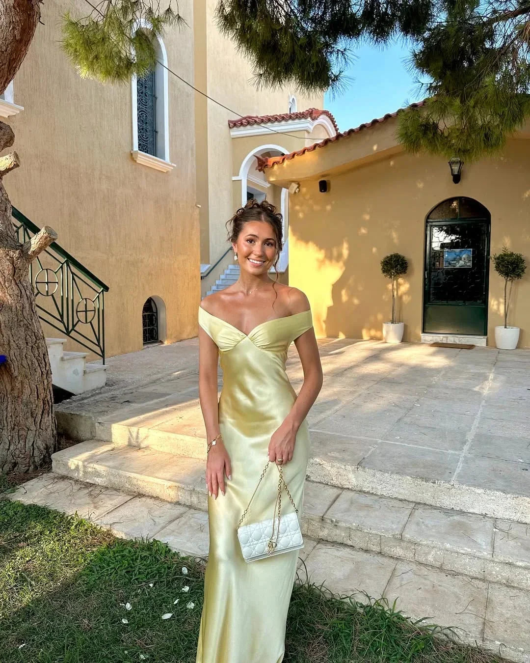 Women's off-shoulder yellow maxi dress with matching clutch; chic design, flowing silhouette, perfect for elegant events.