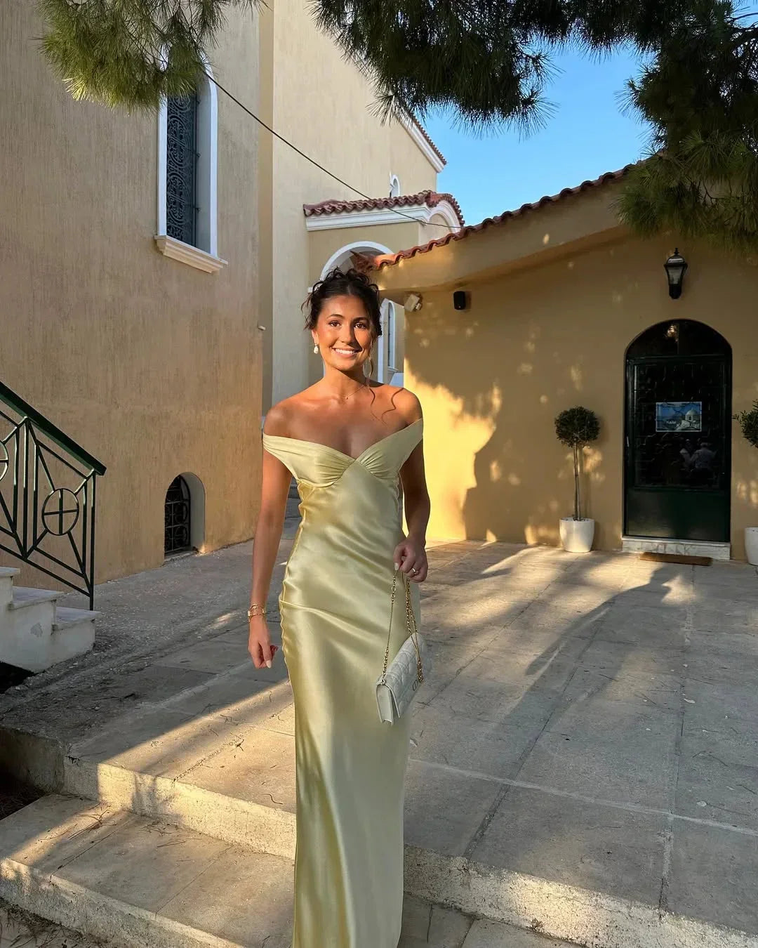 Women's off-shoulder yellow maxi dress with matching clutch; chic design, flowing silhouette, perfect for elegant events.