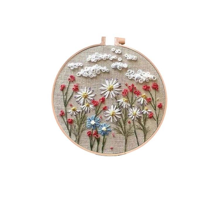 Hand holding a needle, ready to stitch a beautiful floral design from an embroidery kit.
