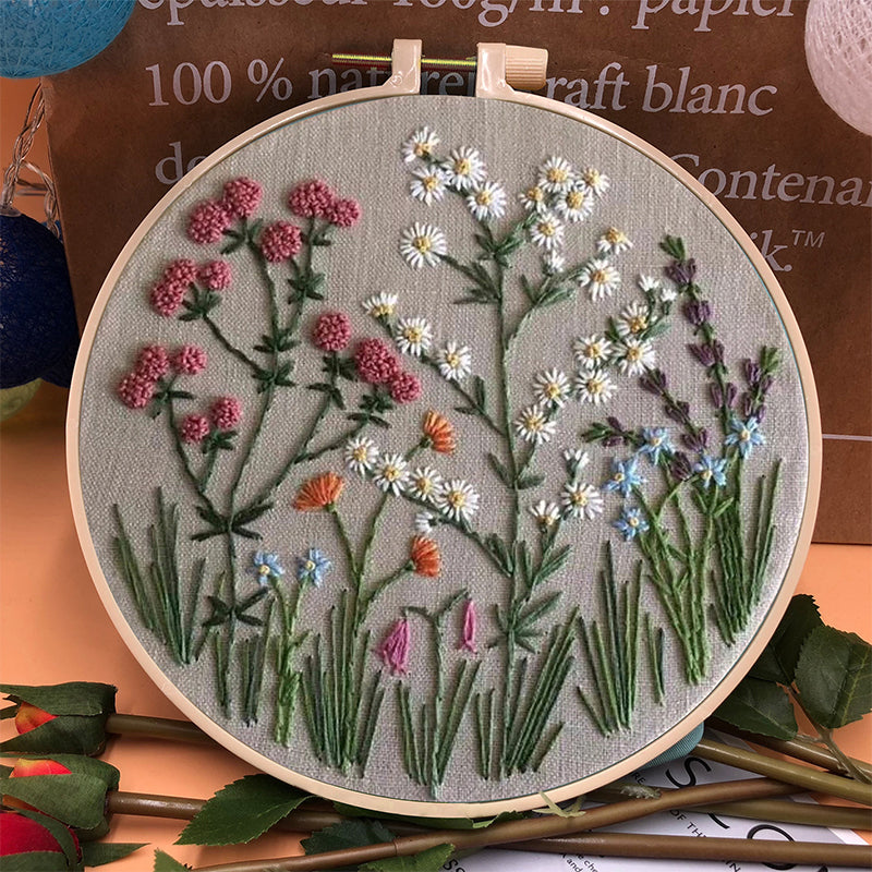 Complete beginner's floral embroidery kit with fabric, needles, colorful threads, and instructions.