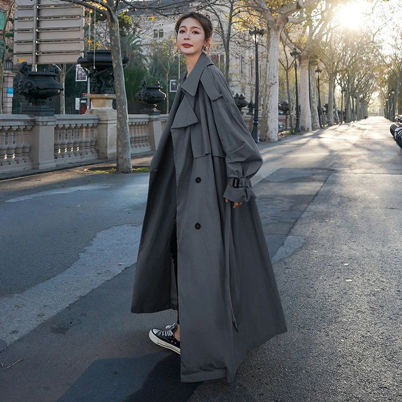 Fashionable women's long trench coat, double-breasted and loose-fit, ideal for a chic outerwear look.