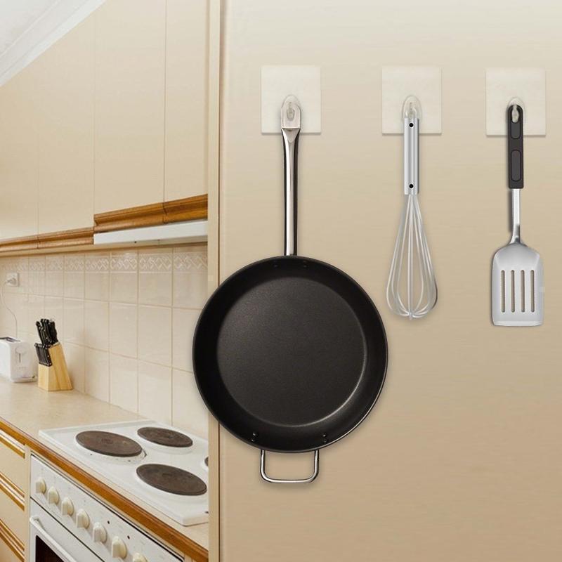Person applying a clear seamless sticky wall hook on a kitchen backsplash, easy peel-and-stick install