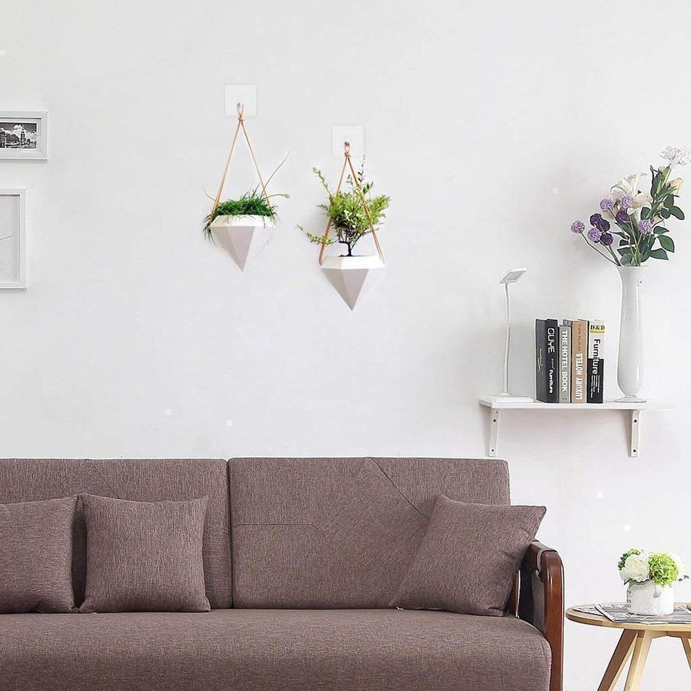 Two clear sticky hooks holding a framed picture without drilling, transparent home decor hanger