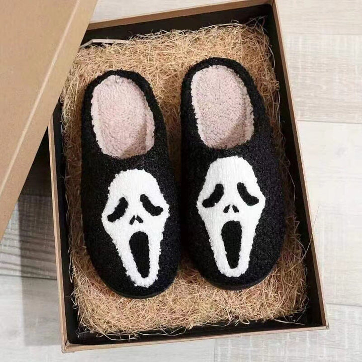 Top-down view of women's Halloween plush slippers, one pumpkin, one ghost design.
