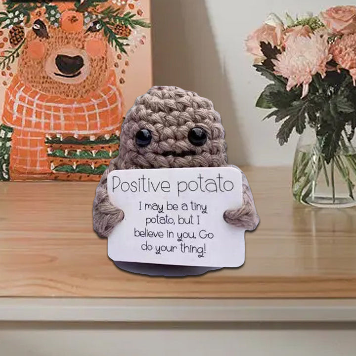 Positive potato knitted doll next to a plant, bringing cheer and motivational encouragement to any space.