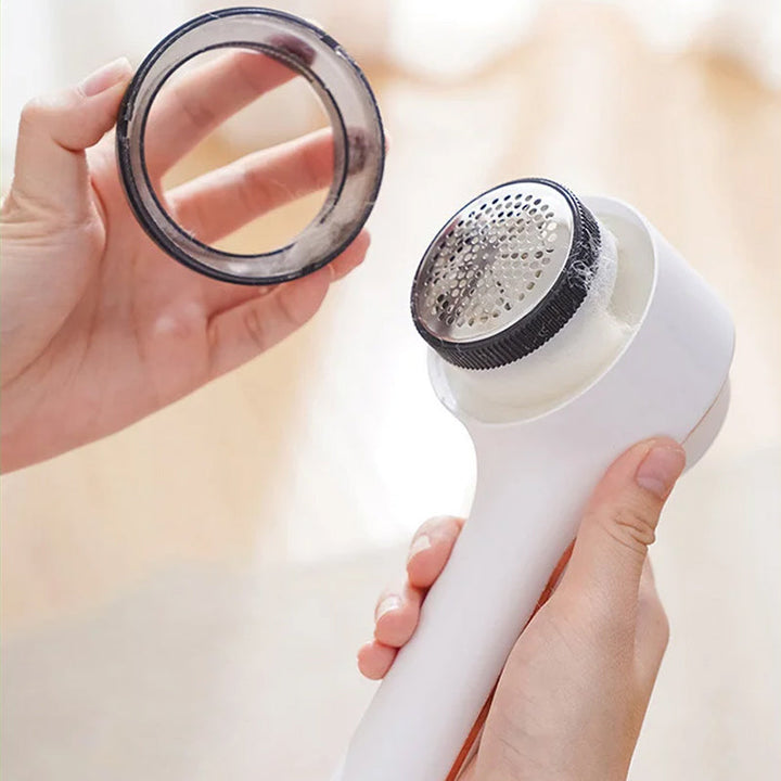 Hand holding Electric Clothes Lint Remover Fabric Shaver, demonstrating its compact size and portability