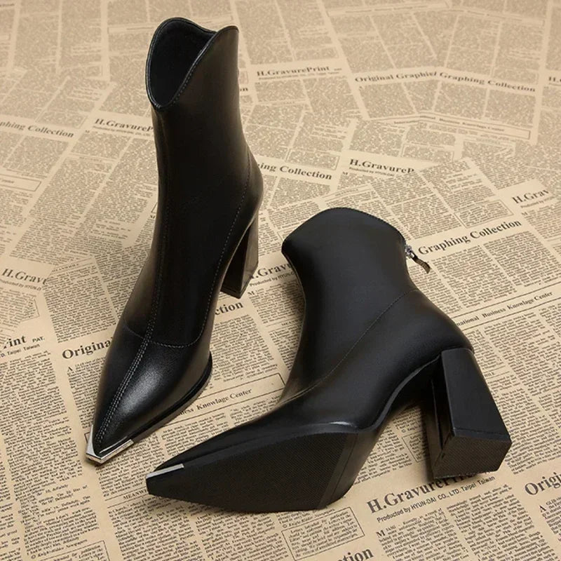 Close-up of a women's black ankle boot, highlighting the pointed toe and textured block heel.