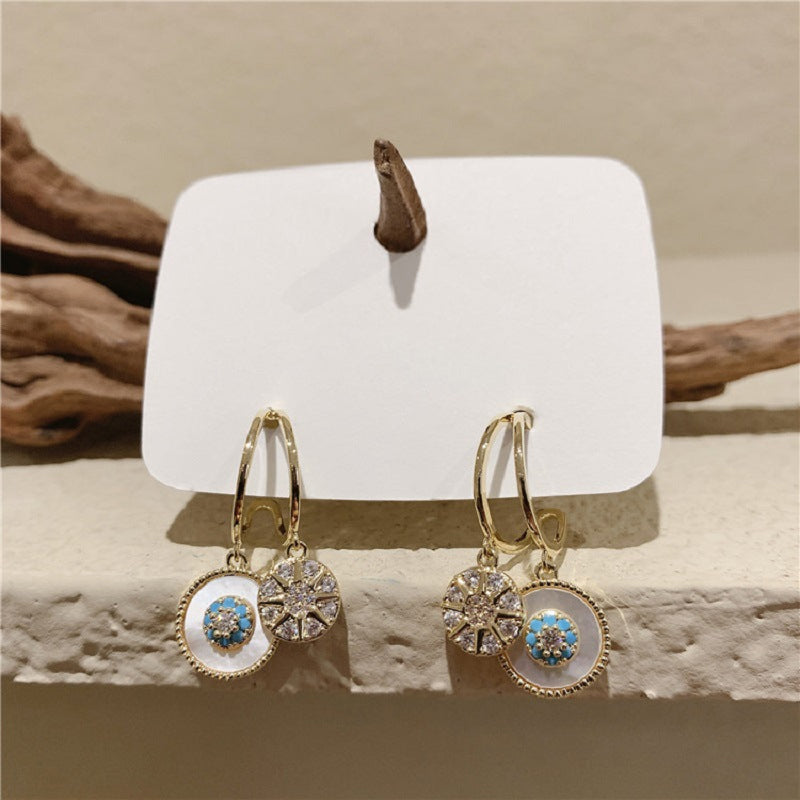 Detailed shot of a single gold dangle earring with a graceful leaf and sea design