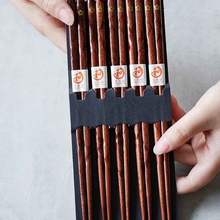 Five pairs of elegant wooden dining chopsticks, featuring a golden cherry blossom design, perfect for tableware.