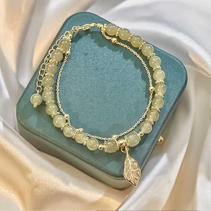 Hand modeling an elegant Women's Hetian jade bracelet with shimmering gold leaf, chakra jewelry