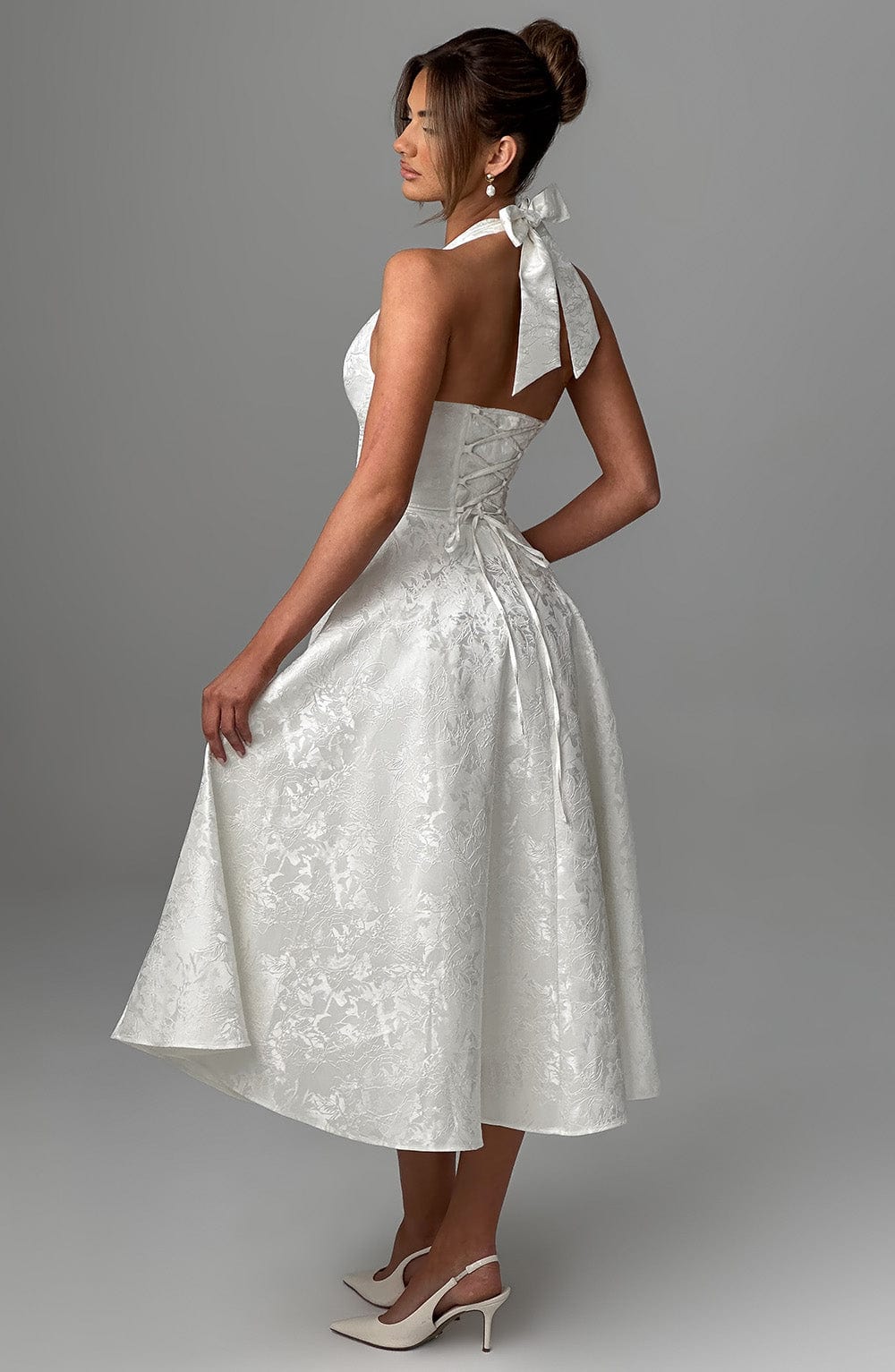 Woman posing in a sophisticated white halter neck midi dress, ideal for formal events.