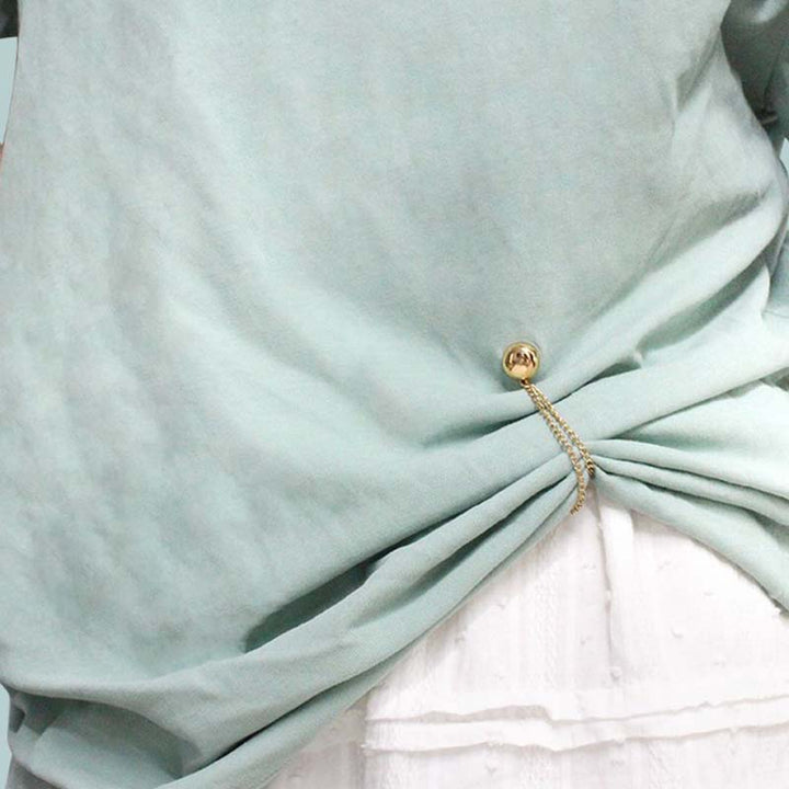 Versatile magnetic clips for clothing, shown holding a scarf in place and cinching a cardigan.