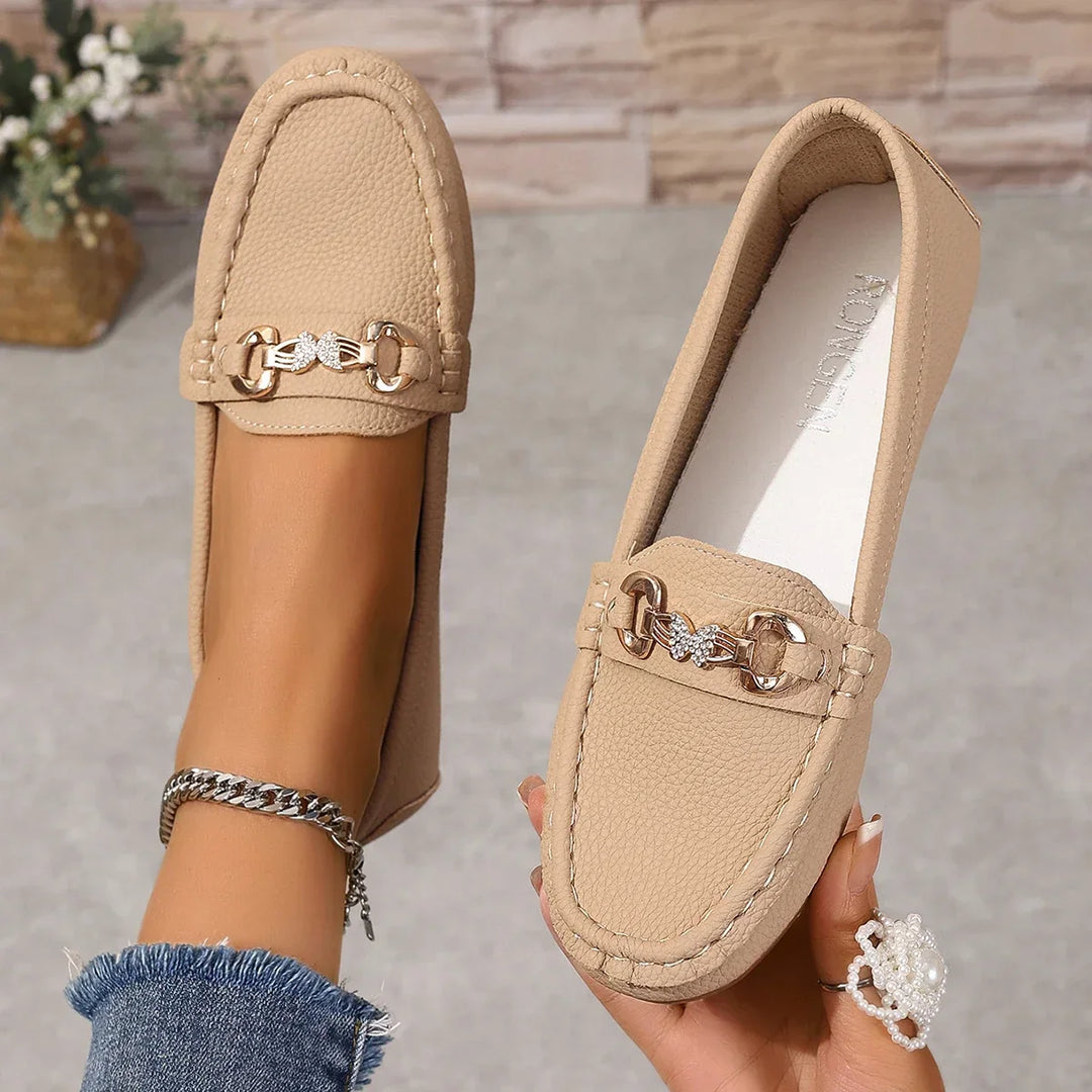 Close-up of the crystal chain detail on elegant women's black faux leather loafers.