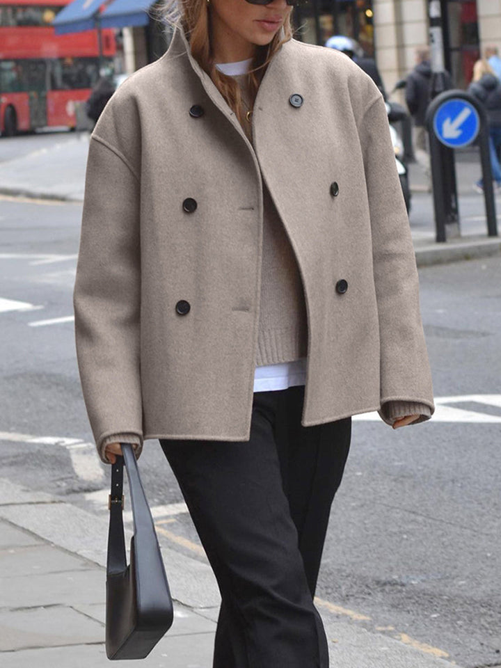 Close-up of a women's classic double-breasted gray coat, highlighting tailored details and fabric.