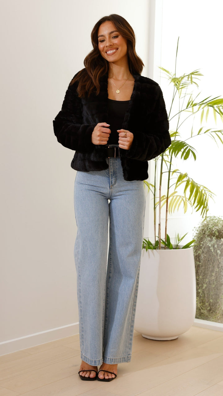 Rear view of a women's elegant cropped faux fur jacket, showcasing its design.