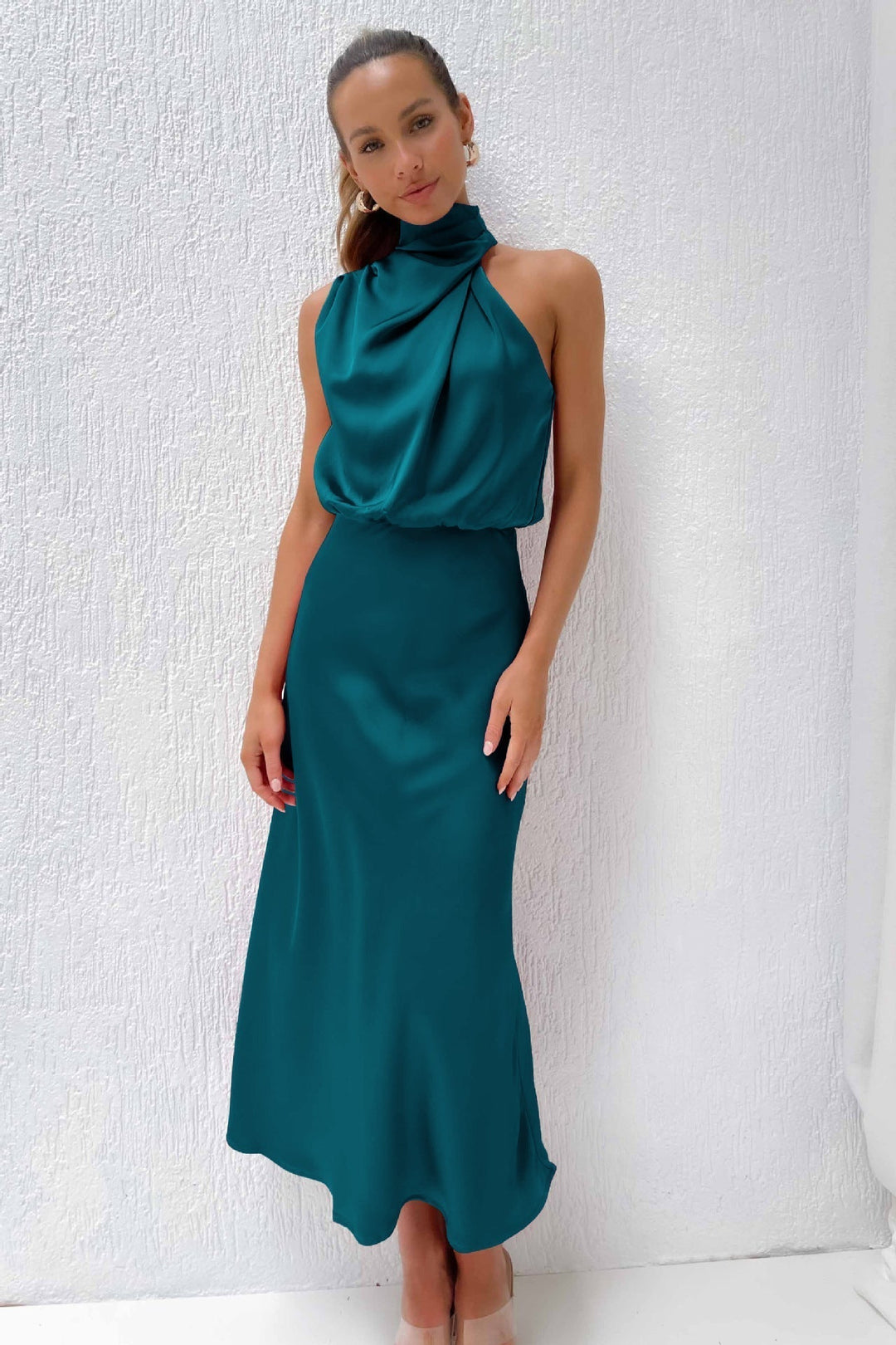Woman modeling an elegant halter evening gown, floor-length with an open back, perfect for galas.