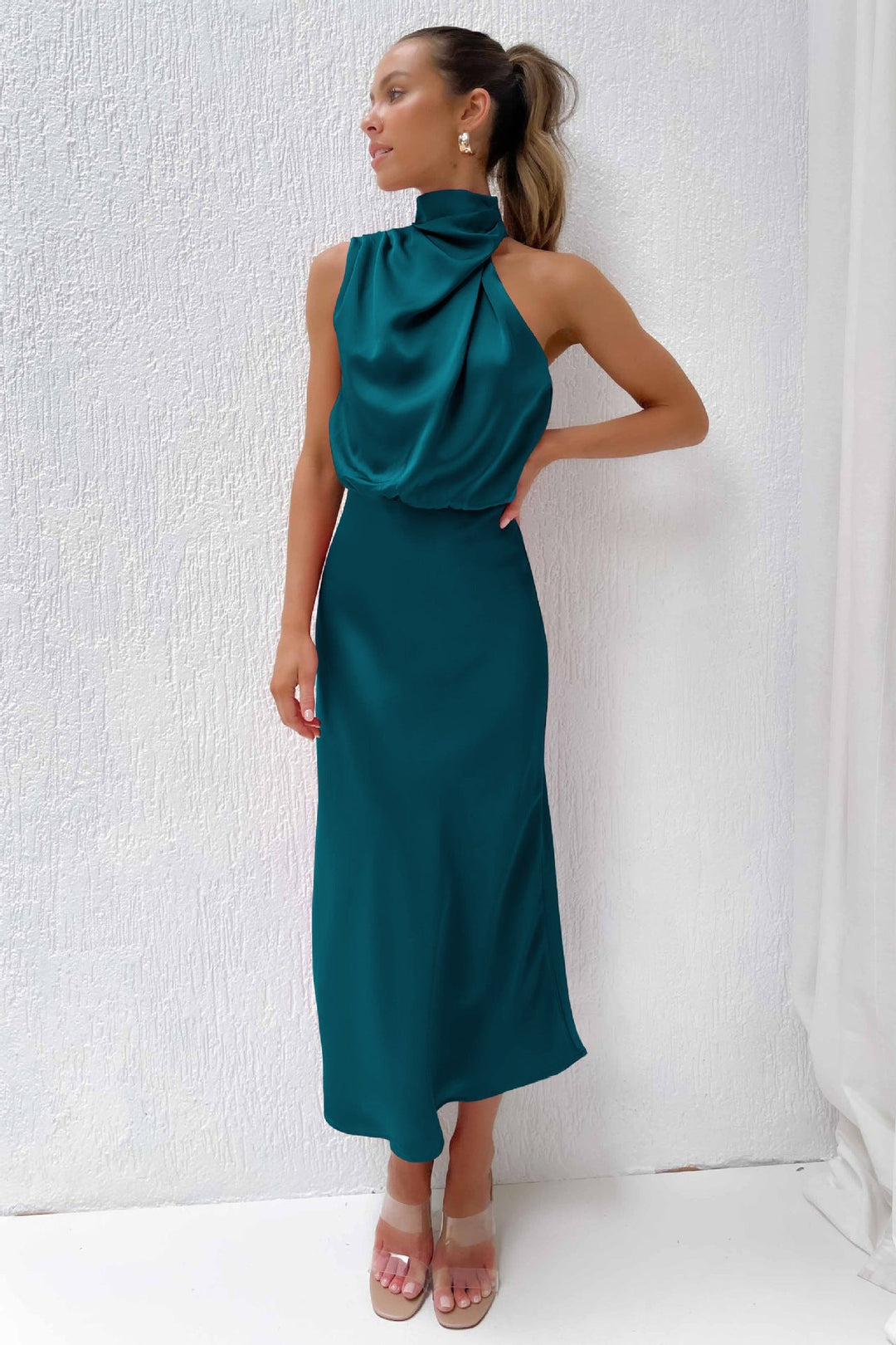 Flowing women's halter evening gown in motion, elegant open back & floor-length, ideal for dancing.