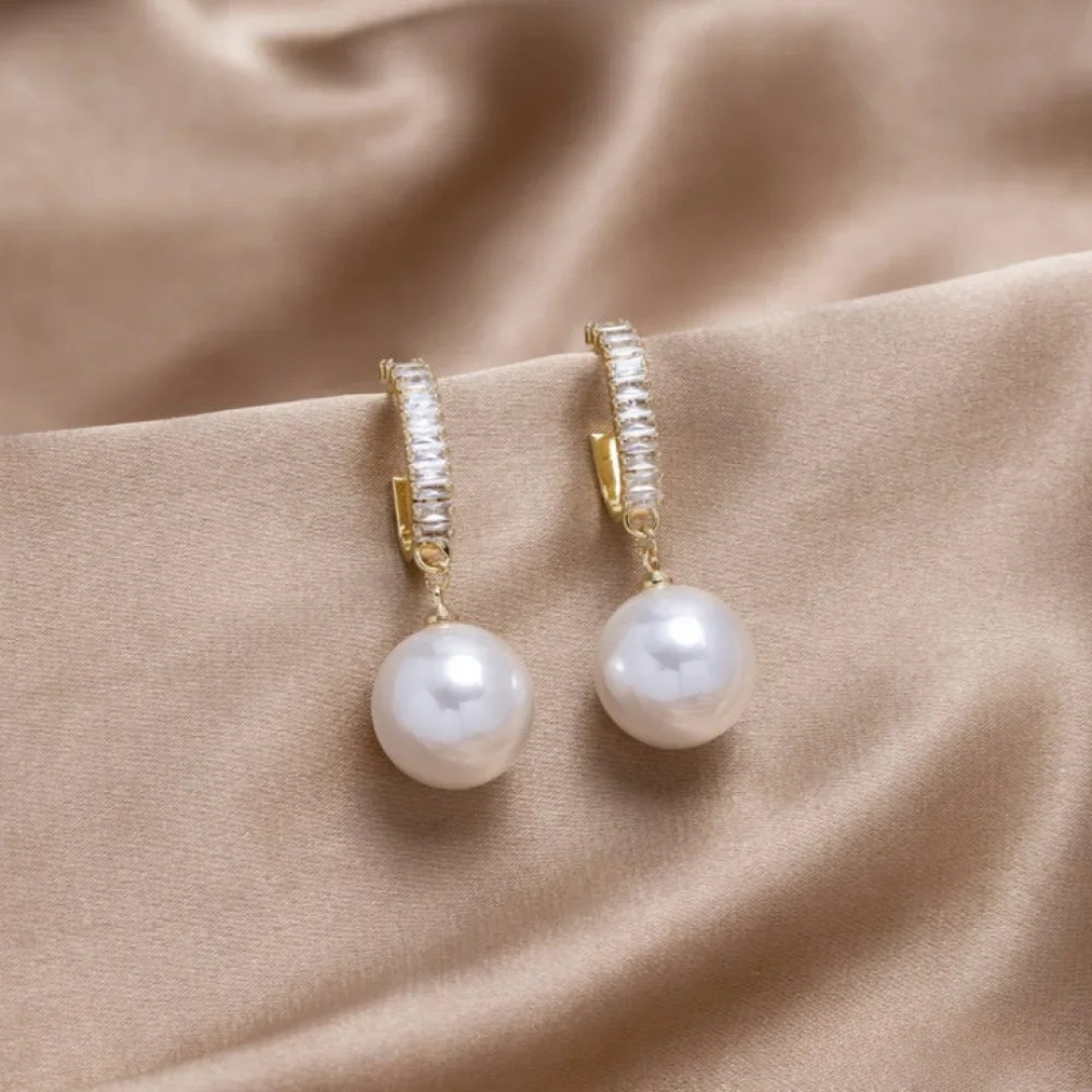 Elegant women's pearl and sparkling zirconia drop earrings. Stylish special occasion jewelry accessory.