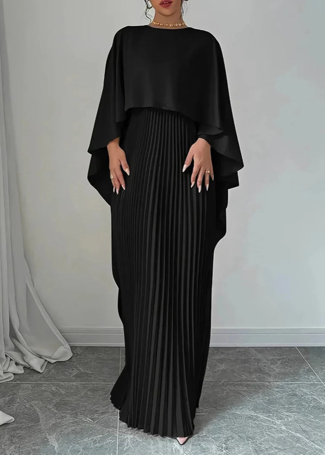 Long elegant women's dress, pleated and adorned with a graceful cape overlay, suitable for formal events.