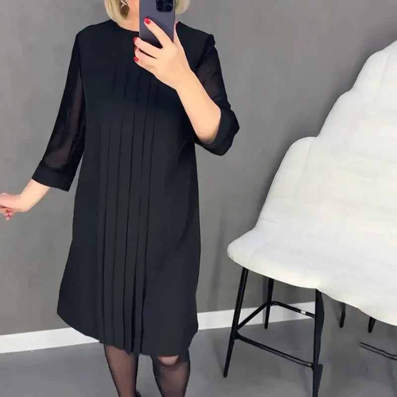 Close-up of the pleated detail on a women's round neck midi dress, showing texture