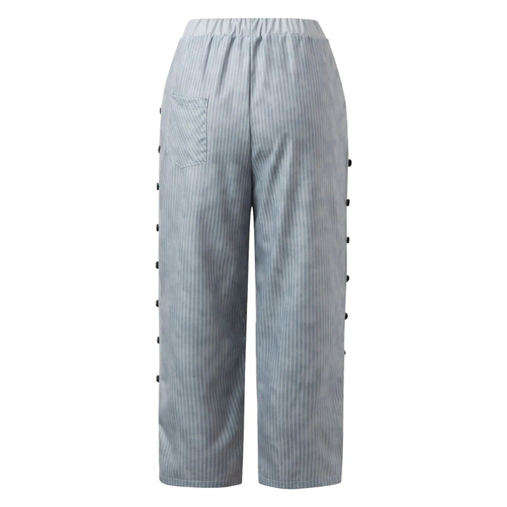 Modern women's striped high-waist trousers featuring decorative buttons. A key piece for elegant spring fashion.