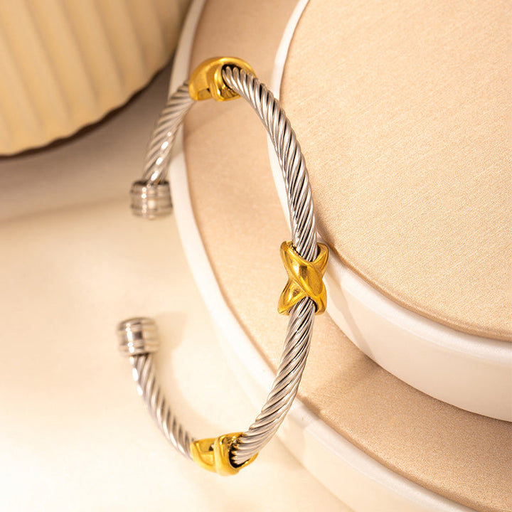 Fashionable women's two-tone bangle bracelet featuring an intricate twisted knot.