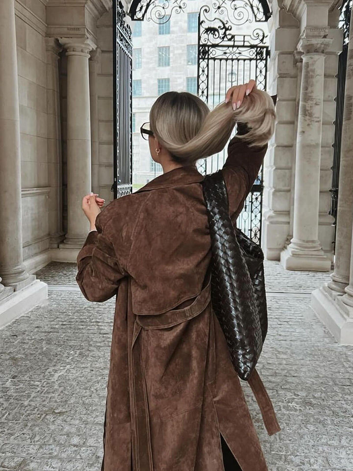 Close-up of the belt detail on a women's warm brown midi trench coat, classic and chic.
