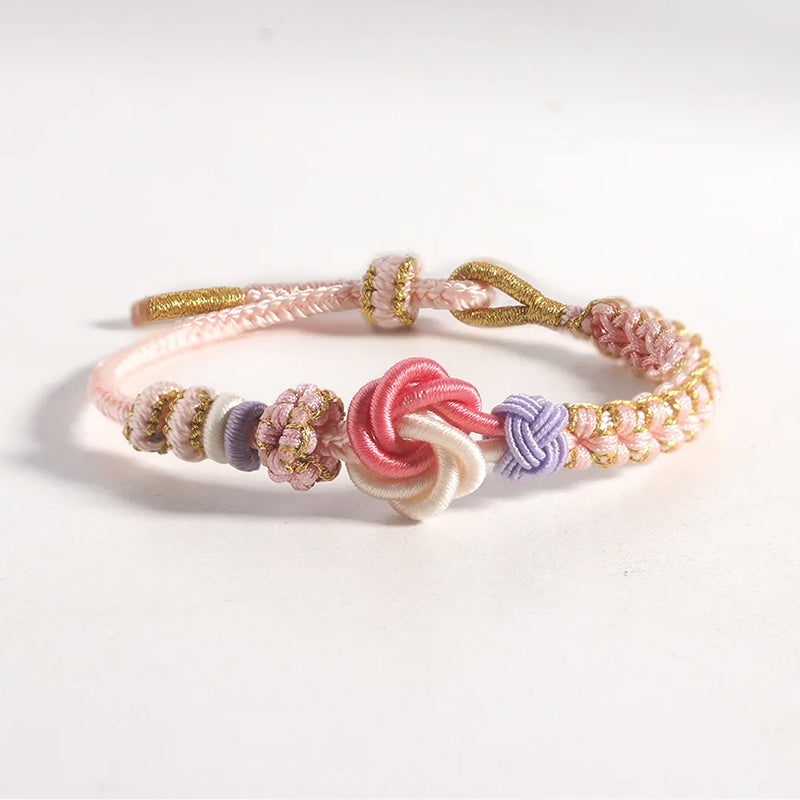 Hand holding a peach blossom knot braided bracelet, showing its lightweight nature, comfortable for girls