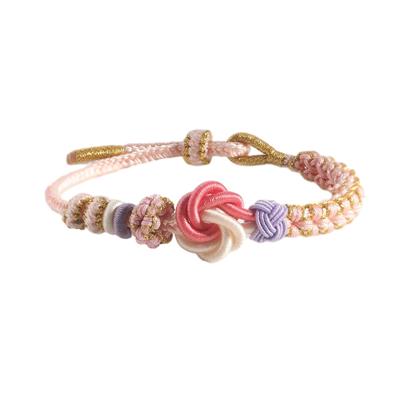 Toddler girl wearing a peach blossom knot braided bracelet, showing comfortable & adjustable fit on wrist