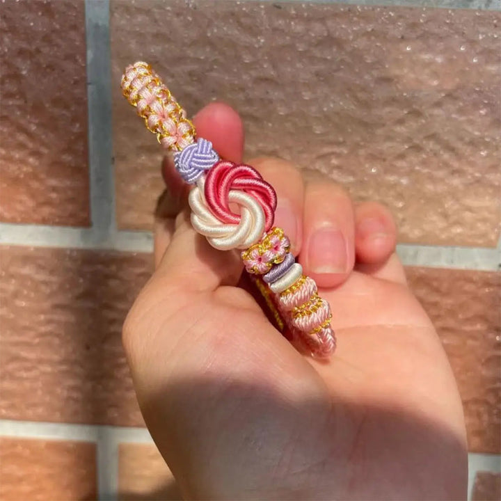 Girl's hand showcasing a peach blossom knot braided bracelet, highlighting adjustable cord and secure knot