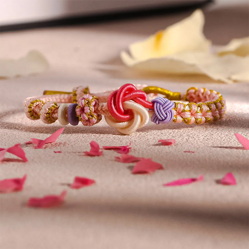 Overhead view of a peach blossom knot braided bracelet on a white background, clean & simple kids' jewelry