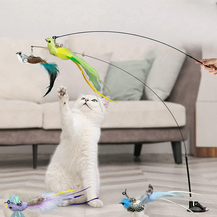 A cat playfully batting at the feathered bird design of an interactive wand toy with suction cup.