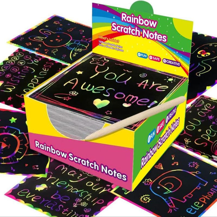 Child's hands holding a scratching tool and a rainbow scratch art sheet, focused on creative play