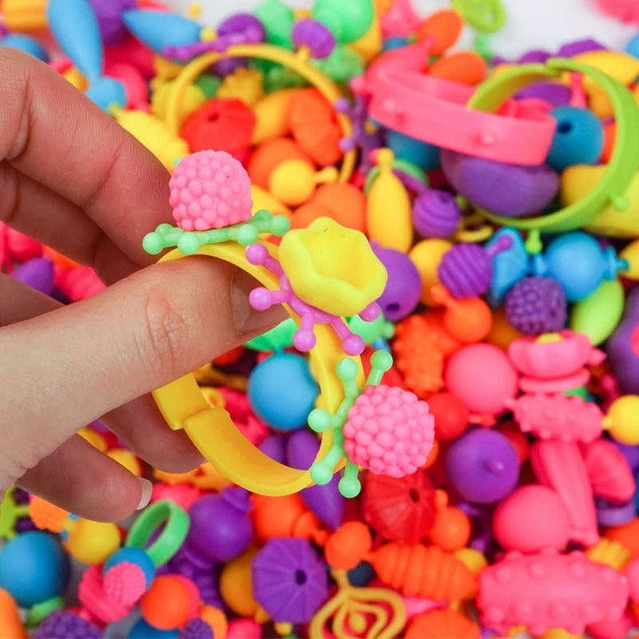 Overhead shot of an organized pop bead craft station, featuring the Kids' DIY Snap Beads Jewelry Making Kit components