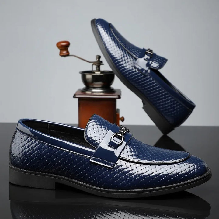 Detail shot of the polished silver bit on men's embossed leather loafers, highlighting premium quality.