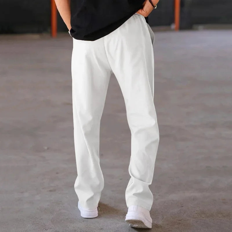 Stack of folded men's loose-fit formal trousers in assorted colors, ready for retail display.