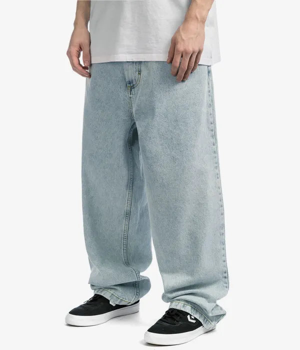 Stack of men's relaxed wide-leg denim pants in varying light washes, essential for spring fashion.
