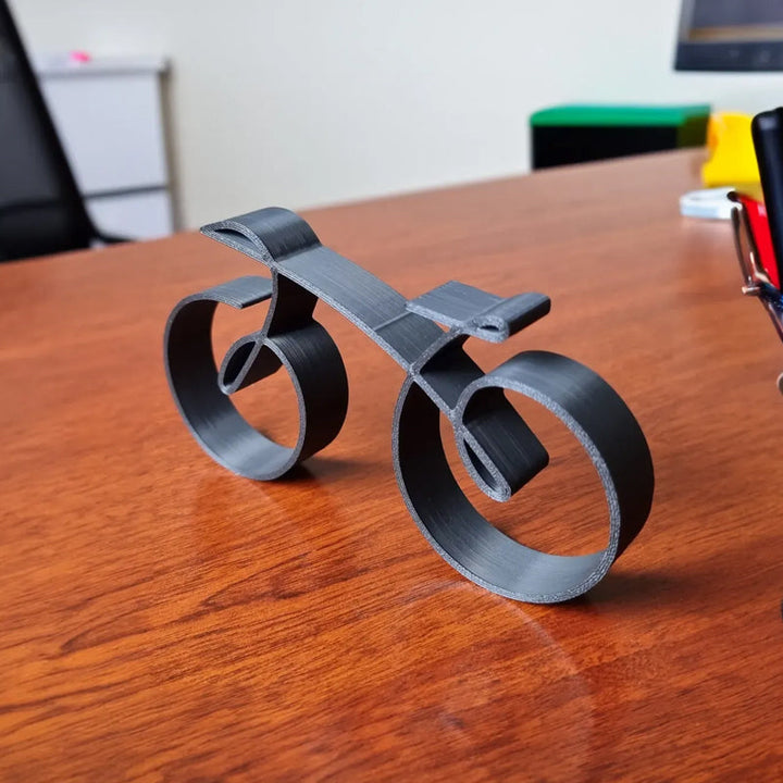 Minimalist bicycle sculpture on a wooden desk, sleek metal art elevating office decor, cyclist gift