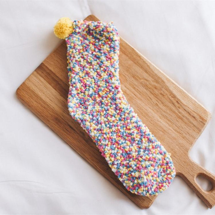 Detailed shot of the 'icing' and 'sprinkle' embellishments on the women's cupcake slipper socks.