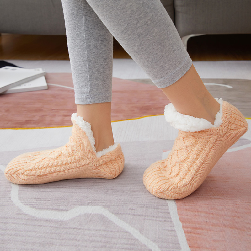 Model wearing warm grey unisex slipper socks while relaxing on a sofa, emphasizing home essential comfort.