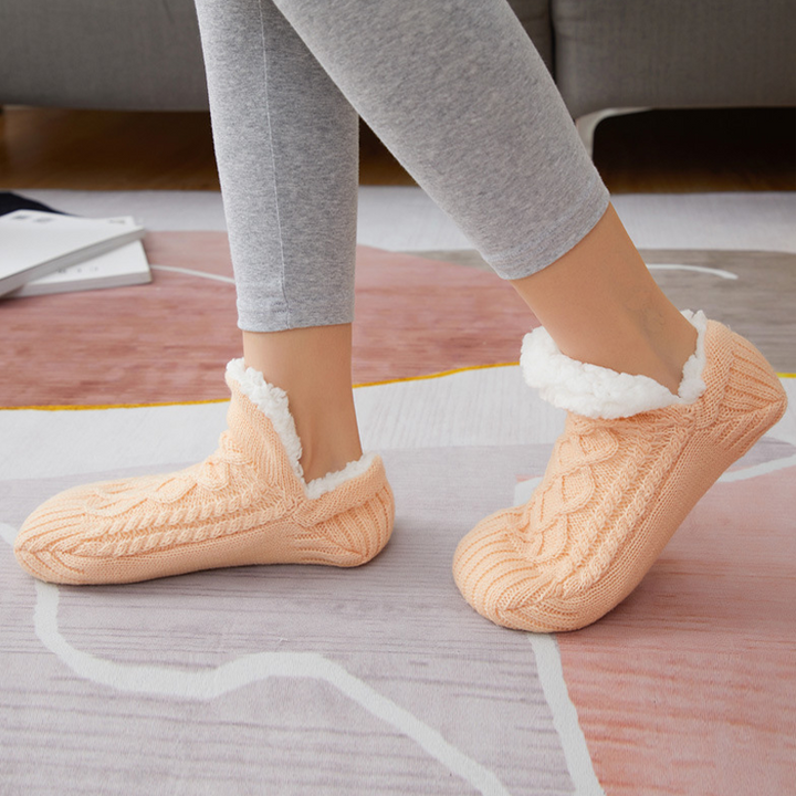 Model wearing warm grey unisex slipper socks while relaxing on a sofa, emphasizing home essential comfort.