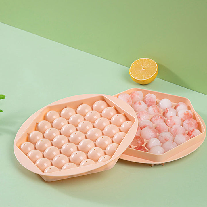 Two sphere ice maker molds, pink and blue, for making round ice balls in the freezer.