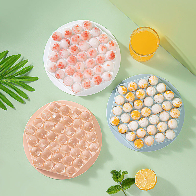 Set of two sphere ice maker molds, one pink and one blue, for cocktails.