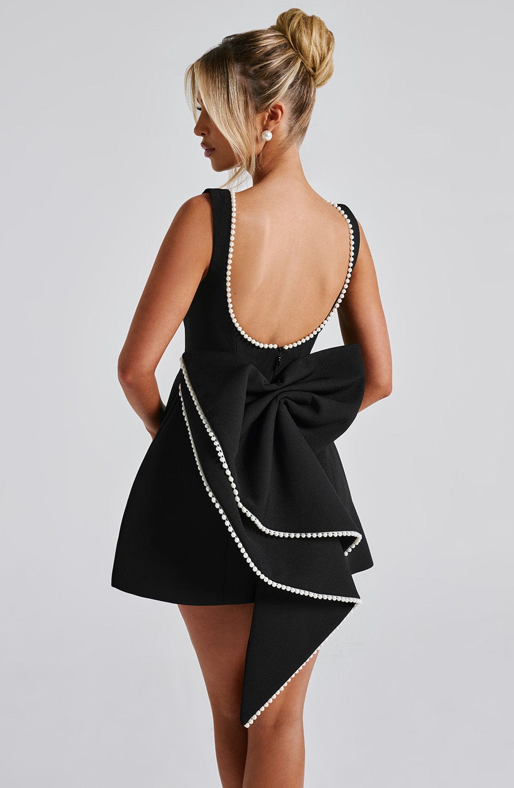 Model wearing a black structured mini dress, showcasing the fit and style for a wedding guest event.